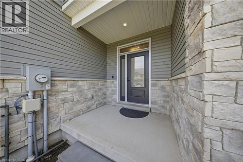 Inviting front entry featuring a concrete porch, dark gray entry door with partial glass, integrated sidelight, and an overhead porch light - 107 Stephenson Way, Palmerston, ON - Outdoor With Exterior