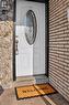 Entryway featuring a white door with decorative oval glass insert, brass hardware, and a porch light - 8 Robins Avenue, Hamilton, ON  - Outdoor With Exterior 