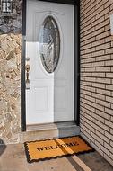 Entryway featuring a white door with decorative oval glass insert, brass hardware, and a porch light - 