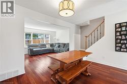 Open concept dining area featuring wood-finish flooring, a decorative ceiling fixture, and access to a living area with large windows - 