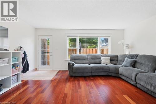Living area featuring rich wood-finish flooring, white walls, and a large window providing natural light - 86 San Remo Drive, Hamilton, ON - Indoor Photo Showing Living Room