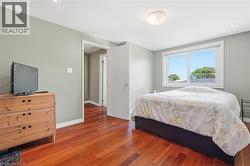Spacious room featuring rich wood-finish flooring, a large window, recessed lighting, and a neutral wall color - 