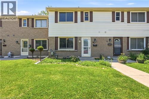 Two-story townhouse exterior featuring brick and siding facade, multiple windows with shutters, and a well-maintained front lawn with a concrete pathway - 86 San Remo Drive, Hamilton, ON - Outdoor With Facade