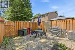 Paved patio area featuring interlocking pavers and a full-height wood fence - 