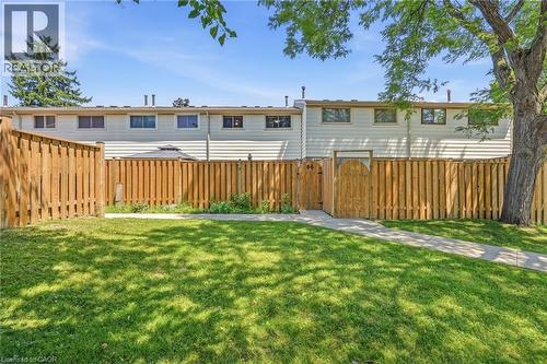 Expansive fenced backyard featuring a manicured lawn, concrete pathway, and a wooden privacy fence with a decorative gate - 86 San Remo Drive, Hamilton, ON - Outdoor