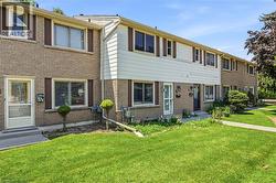 Brick and siding exterior featuring multiple windows with shutters and mature front lawn - 