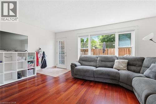 Living area featuring rich wood-finish flooring, white walls, and a large window overlooking a wooden fence - 86 San Remo Drive, Hamilton, ON - Indoor Photo Showing Living Room