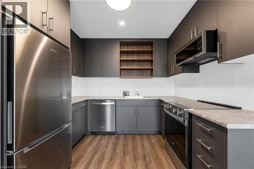 Modern kitchen featuring sleek grey cabinetry with brushed nickel hardware, stainless steel appliances, light-toned countertops, and wood-finish flooring - 146 Everett Common, St. Catharines, ON - Indoor Photo Showing Kitchen With Stainless Steel Kitchen