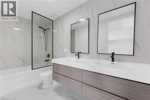 Floating dual vanity with integrated sinks, wood-grain cabinetry, and matte black fixtures - 146 Everett Common, St. Catharines, ON - Indoor Photo Showing Bathroom