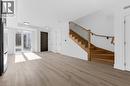Open-concept living space with light wood-finish flooring, a modern wooden staircase with black iron balusters, white walls, and recessed lighting - 146 Everett Common, St. Catharines, ON  - Indoor Photo Showing Other Room 