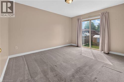 Carpeted room featuring neutral wall paint, white baseboards, and a glass sliding door with beige drapes - 186 Glenmor Drive, Caledonia, ON - Indoor Photo Showing Other Room