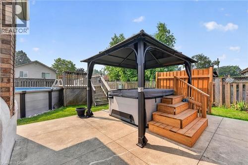 Backyard oasis featuring a covered hot tub, concrete patio, above-ground pool with surrounding deck, and privacy fencing - 186 Glenmor Drive, Caledonia, ON - Outdoor With Deck Patio Veranda With Exterior