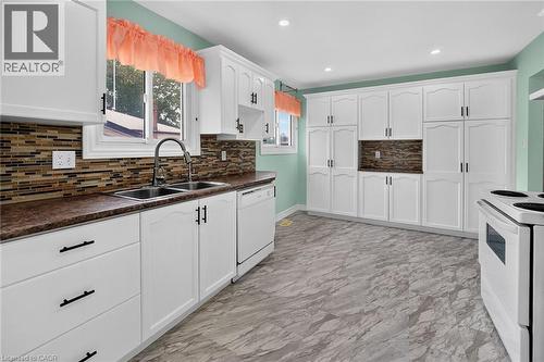 Kitchen featuring extensive white cabinetry with black hardware, mosaic tile backsplash, dual basin sink, and wood-finish countertops - 186 Glenmor Drive, Caledonia, ON - Indoor Photo Showing Kitchen With Double Sink
