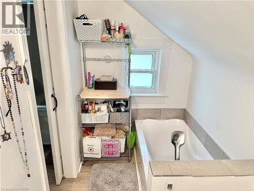 Second floor Bathroom featuring a built-in soaking tub, tiled surround, and a double-hung window with decorative trim - 88 Brook Street, Simcoe, ON - Indoor Photo Showing Bathroom