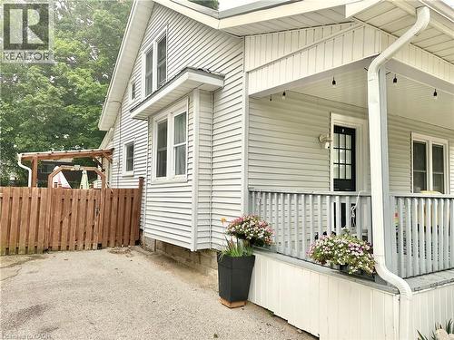 White siding exterior featuring a covered front porch with railings, black front door, and multiple windows - 88 Brook Street, Simcoe, ON - Outdoor