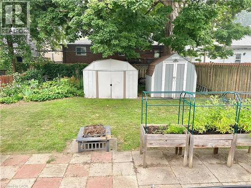 Expansive backyard featuring a lush lawn, two storage sheds, a stone patio, and raised garden beds - 88 Brook Street, Simcoe, ON - Outdoor