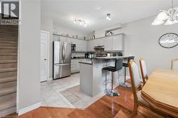 Kitchen featuring stainless steel appliances, light gray cabinetry, and a breakfast bar with seating - 