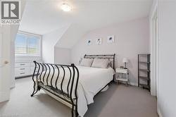 Carpeted bedroom featuring an angled ceiling, window with horizontal blinds, built-in dresser with dark hardware, and a semi-flush mount ceiling light fixture - 