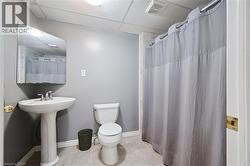 Full bathroom featuring a pedestal sink with a chrome faucet, a white toilet, and a shower area with a curtain rod - 