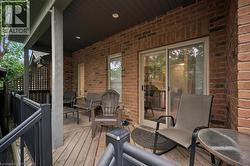 Covered outdoor deck with brick exterior, wood-finish flooring, and sliding glass door access - 