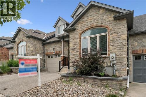 Stone facade residence featuring a single-car garage, dormer windows, and an arched window - 23 Knack Lane, Cambridge, ON - Outdoor