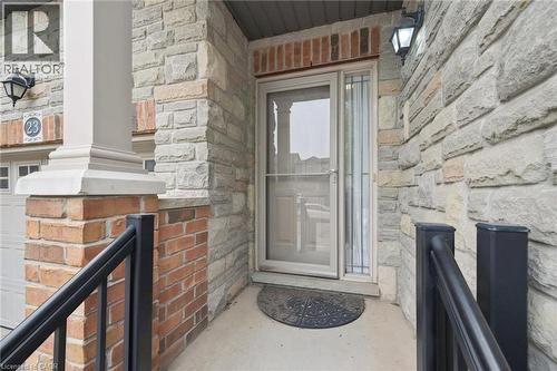 Stone and brick facade entryway featuring a storm door, an exterior light fixture, and a black metal handrail - 23 Knack Lane, Cambridge, ON -  Photo Showing Other Room With Fireplace