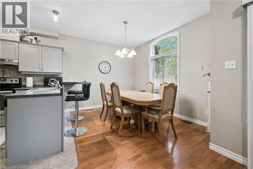 Open-concept kitchen and dining area featuring wood-finish flooring, a kitchen island with seating, pendant lighting, and a large window with an arched transom - 23 Knack Lane, Cambridge, ON - Indoor Photo Showing Dining Room
