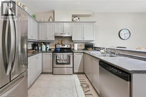 U-shaped kitchen featuring light gray cabinetry, stainless steel appliances, dark speckled countertops, a double basin sink, and tile flooring - 23 Knack Lane, Cambridge, ON - Indoor Photo Showing Kitchen With Double Sink