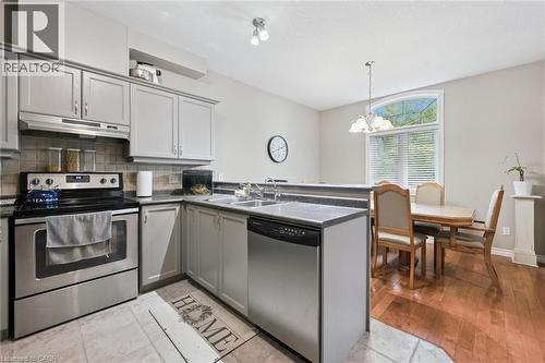 Modern kitchen featuring light gray cabinetry, stainless steel appliances, dark countertops, and tile flooring - 23 Knack Lane, Cambridge, ON - Indoor Photo Showing Kitchen With Double Sink