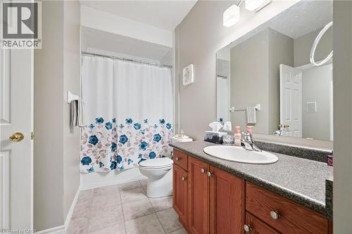 Bathroom featuring a wood-finish vanity with a built-in sink and ample storage, a full-width mirror, and a tub with a shower - 23 Knack Lane, Cambridge, ON - Indoor Photo Showing Bathroom