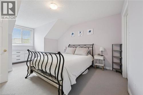 Carpeted bedroom featuring an angled ceiling, window with horizontal blinds, built-in dresser with dark hardware, and a semi-flush mount ceiling light fixture - 23 Knack Lane, Cambridge, ON - Indoor Photo Showing Bedroom