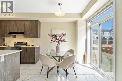 Kitchen and dining area featuring wood-finish cabinetry, light countertops, and white tile flooring - 10 Lemon Avenue, Thorold, ON - Indoor