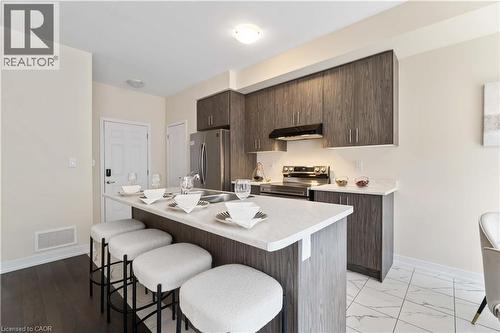 Contemporary kitchen featuring wood-finish cabinetry, stainless steel appliances, a center island with sink, and light-toned countertops - 10 Lemon Avenue, Thorold, ON - Indoor Photo Showing Other Room