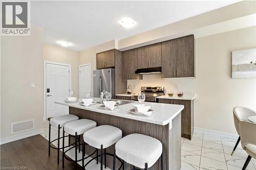 Contemporary kitchen featuring wood-grain cabinetry, stainless steel appliances, and a central island with a white countertop - 10 Lemon Avenue, Thorold, ON - Indoor