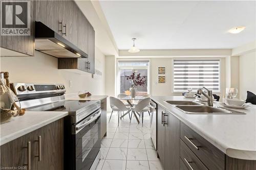 Contemporary kitchen featuring wood-finish cabinetry, light countertops, and white tiled flooring - 10 Lemon Avenue, Thorold, ON - Indoor Photo Showing Kitchen With Double Sink