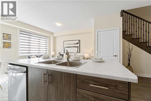 Kitchen island with a double basin sink, integrated dishwasher, and wood-finish cabinetry featuring brass hardware - 10 Lemon Avenue, Thorold, ON - Indoor Photo Showing Kitchen With Double Sink