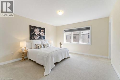 Carpeted bedroom with a large window, light-toned walls, white trim, and a ceiling-mounted light fixture - 10 Lemon Avenue, Thorold, ON - Indoor Photo Showing Bedroom