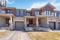 Contemporary brick and stone facade featuring a covered entry, single-car garage, upper-level windows, and a paved driveway - 