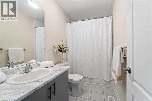 Bathroom featuring a vanity with a faux-marble countertop, an integrated sink, and gray cabinetry with black hardware - 10 Lemon Avenue, Thorold, ON - Indoor Photo Showing Bathroom