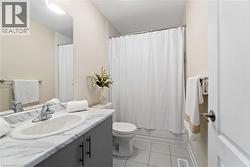 Bathroom featuring a vanity with a faux-marble countertop, an integrated sink, and gray cabinetry with black hardware - 