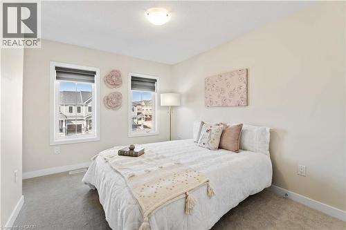 Carpeted room with a ceiling-mounted light fixture and two windows featuring white trim - 10 Lemon Avenue, Thorold, ON - Indoor Photo Showing Bedroom