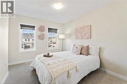Carpeted room with a ceiling-mounted light fixture and two windows featuring white trim - 