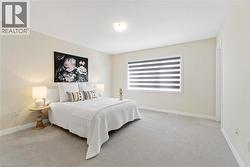 Spacious room featuring neutral painted walls, light gray carpeting, and a window with horizontal blinds - 