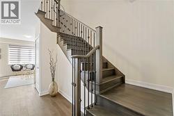 Hardwood staircase featuring dark wood-finish treads and risers, complemented by a black wrought iron baluster system - 