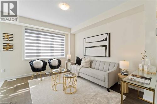 Bright living area featuring wood-finish flooring and a large window with horizontal blinds - 10 Lemon Avenue, Thorold, ON - Indoor Photo Showing Living Room