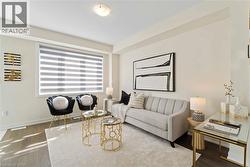 Bright living area featuring wood-finish flooring and a large window with horizontal blinds - 