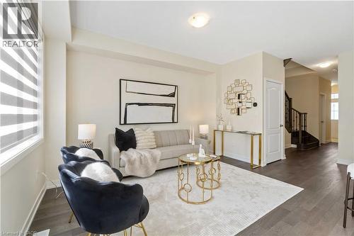 Open-concept living space featuring wood-finish flooring, neutral wall tones, and a staircase with dark wood newel posts and handrails - 10 Lemon Avenue, Thorold, ON - Indoor Photo Showing Living Room