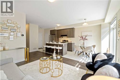 Open-concept living area featuring wood-finish flooring, a contemporary kitchen with a central island and stainless steel appliances, and a dining area with a modern chandelier - 10 Lemon Avenue, Thorold, ON - Indoor Photo Showing Living Room