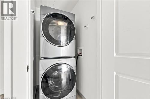 Stacked stainless steel washer and dryer units in a dedicated utility area - 50 Grand Avenue S Unit# 713, Cambridge, ON - Indoor Photo Showing Laundry Room