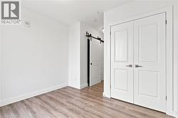 Interior space featuring wood-finish flooring, white baseboards, and bright white walls - 